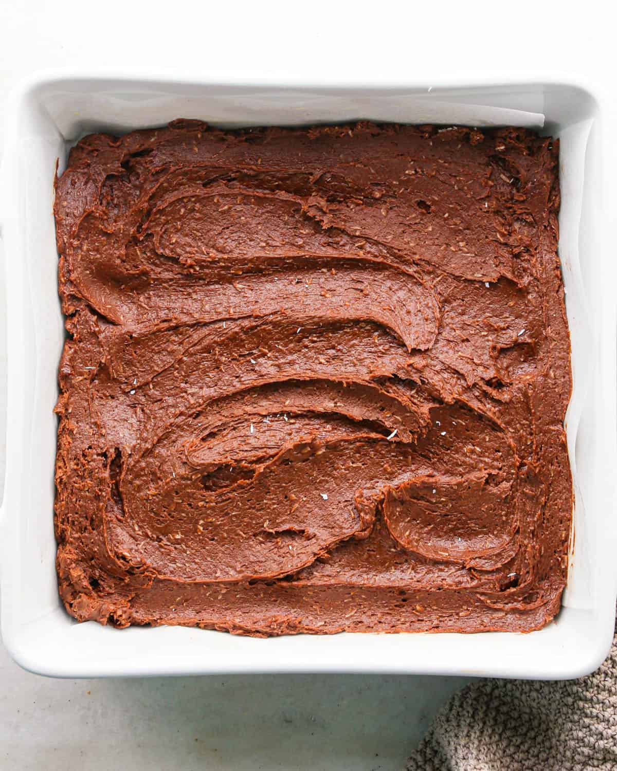 coconut brownies in a white square baking dish before baking