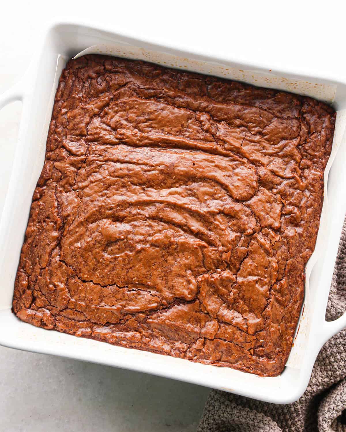 coconut brownies in a white square baking dish after baking