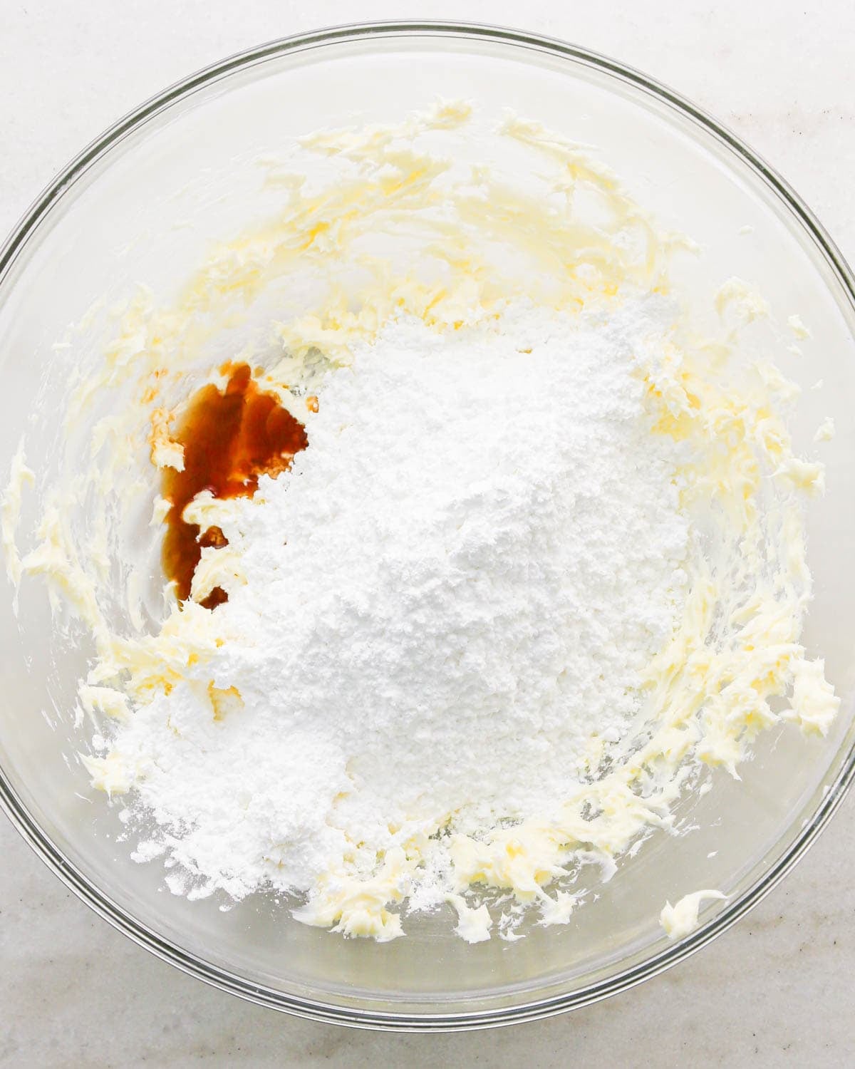 making coconut frosting for coconut brownies - vanilla and powdered sugar added to beaten butter in a glass bowl before mixing