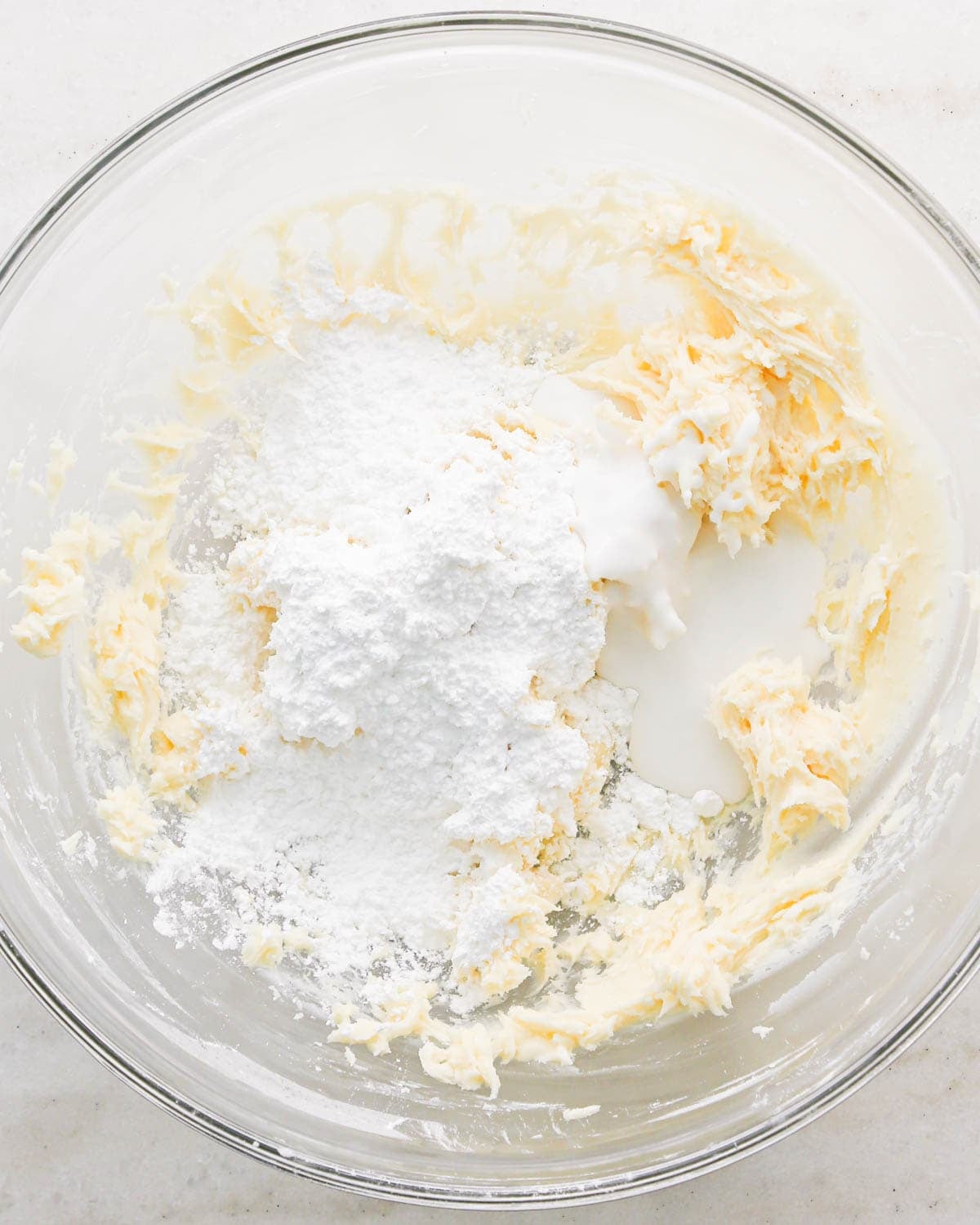 making coconut frosting for coconut brownies - coconut milk and powdered sugar added to beaten butter in a glass bowl before mixing