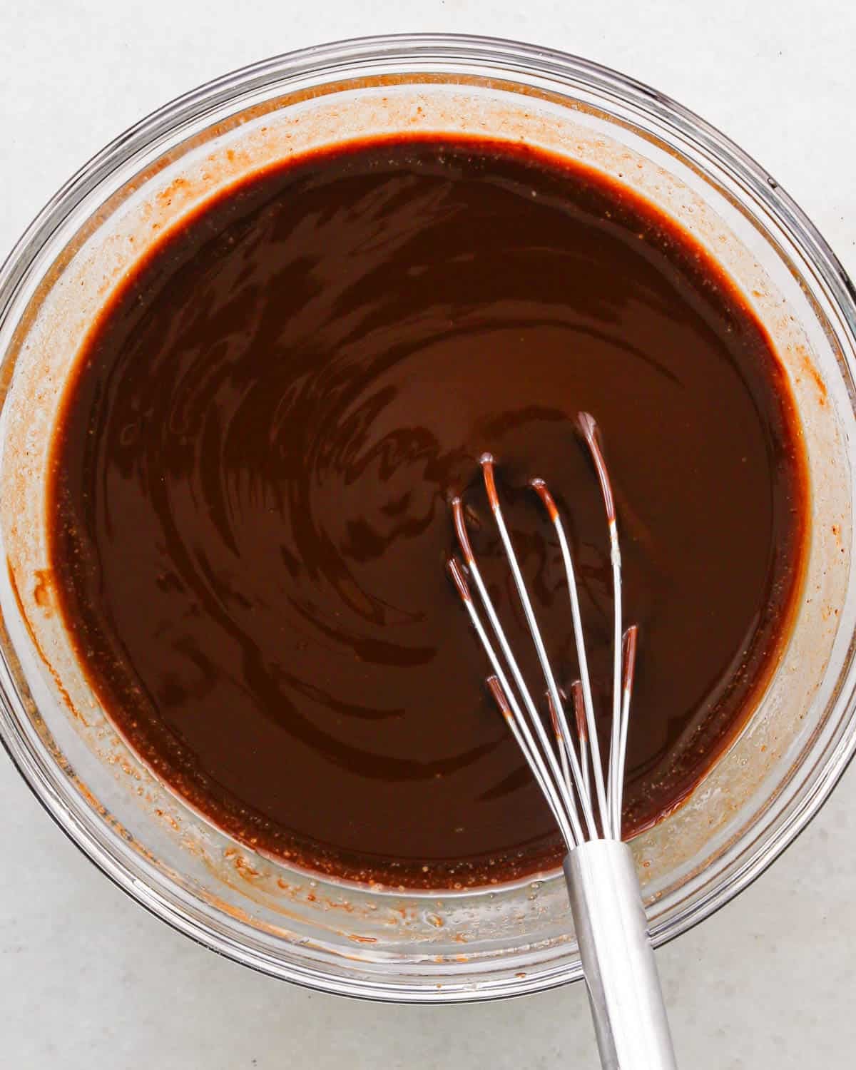 making coconut brownies - butter and chocolate melted in a glass bowl with a wire whisk