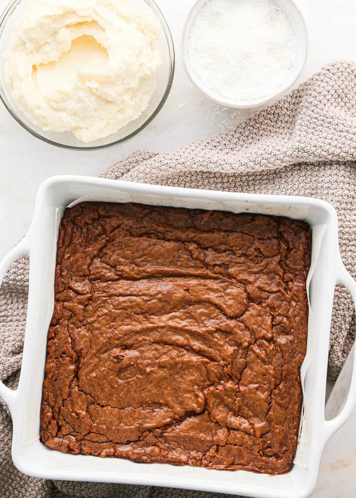 coconut brownies in a pan and coconut frosting in a bowl