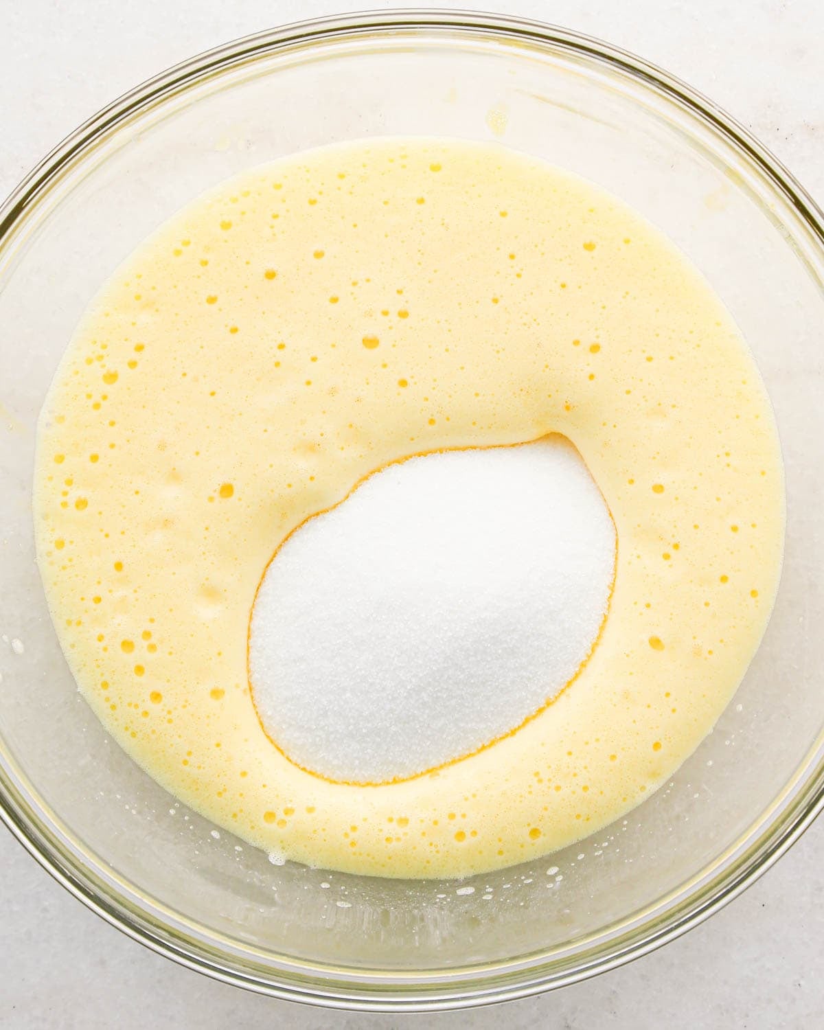 making coconut brownies - white sugar added to beaten eggs in a glass bowl before mixing