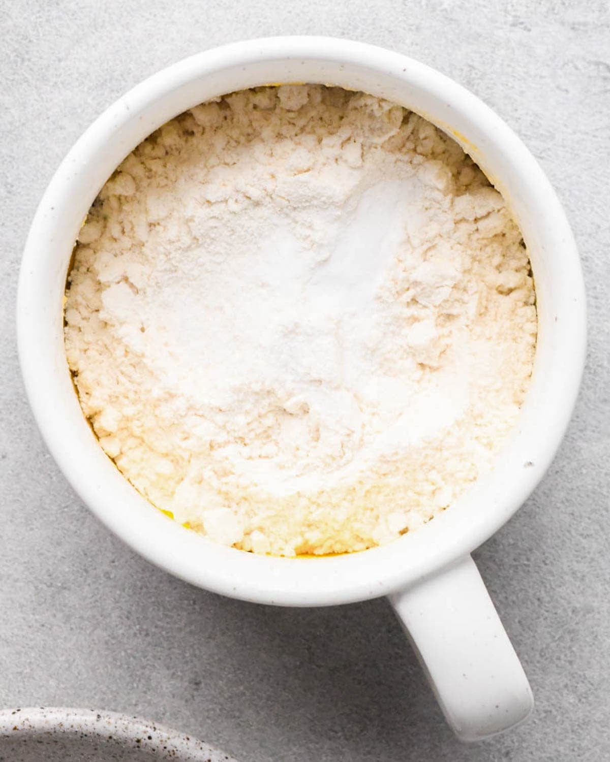 making a cookie in a mug - flour, salt and baking soda added to a white mug before mixing