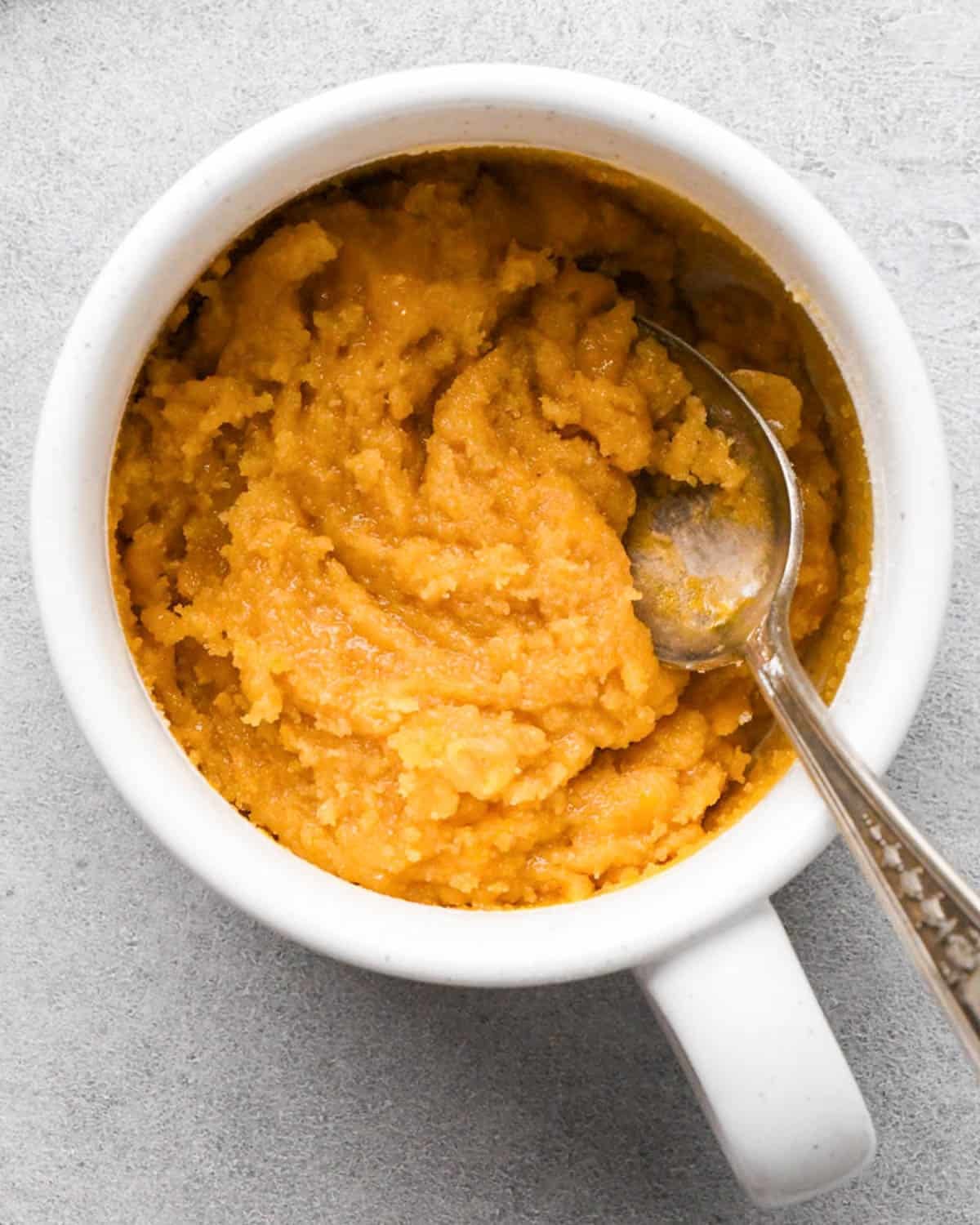 making a cookie in a mug - dough in a white mug with a silver spoon