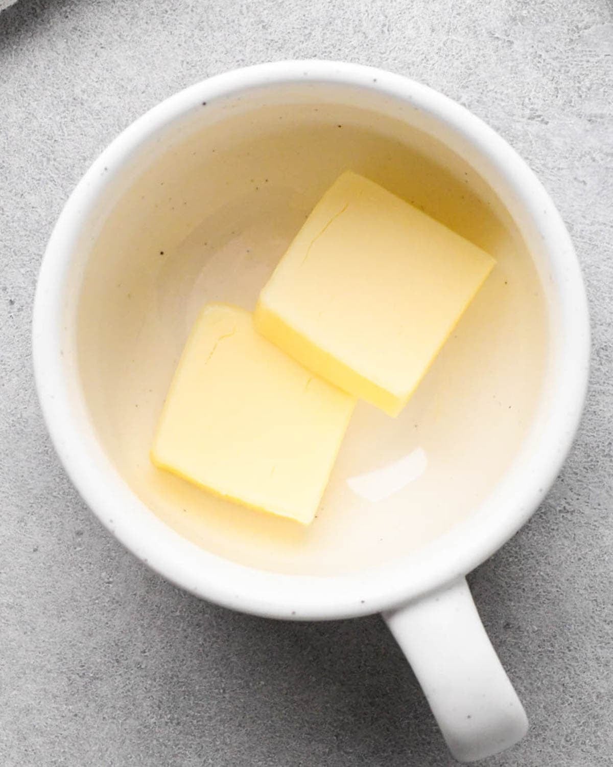making a mug cookie - 2 tablespoons of butter in two squares in a white mug