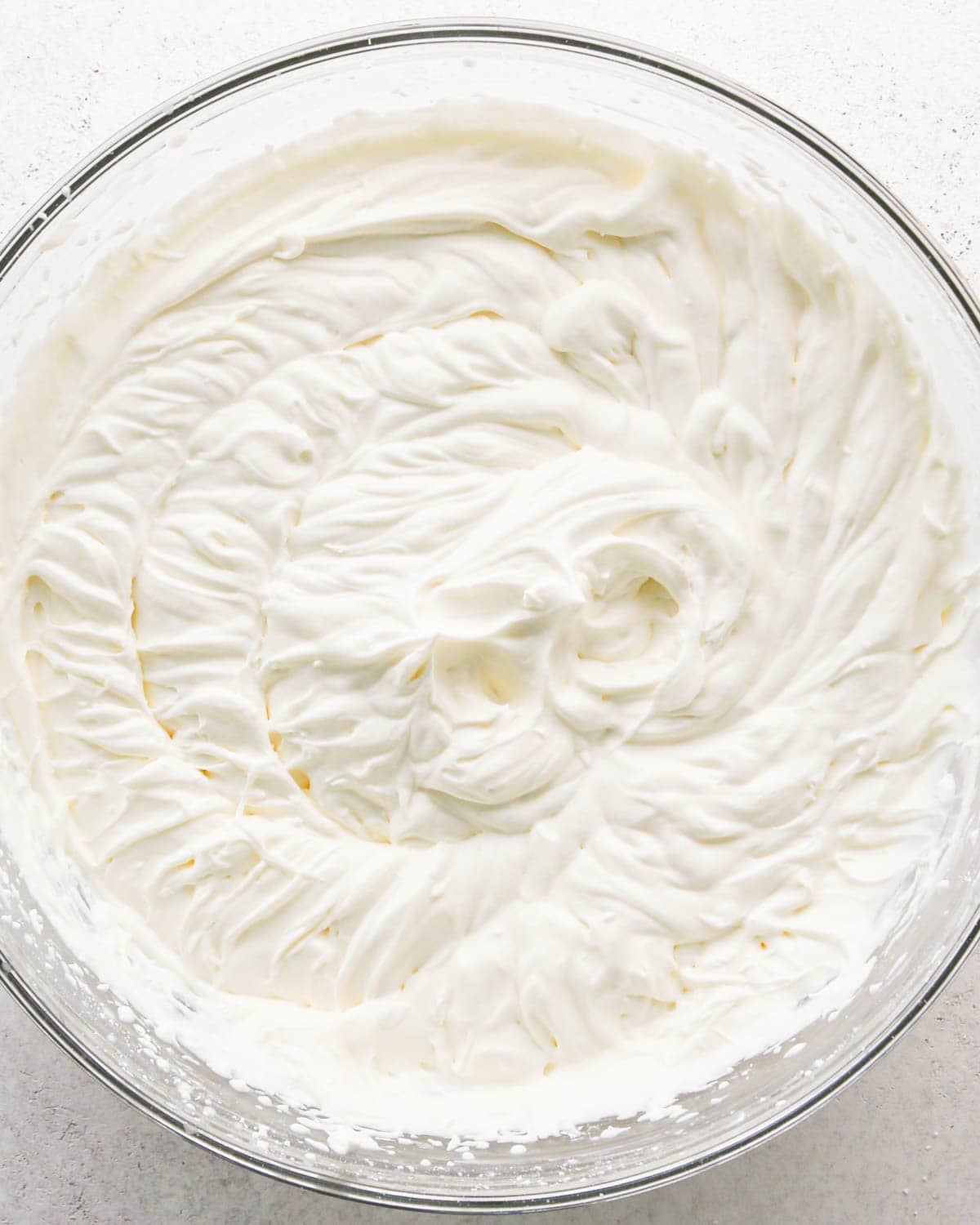 how to make a trifle with berries - final whipped cream layer in a glass bowl