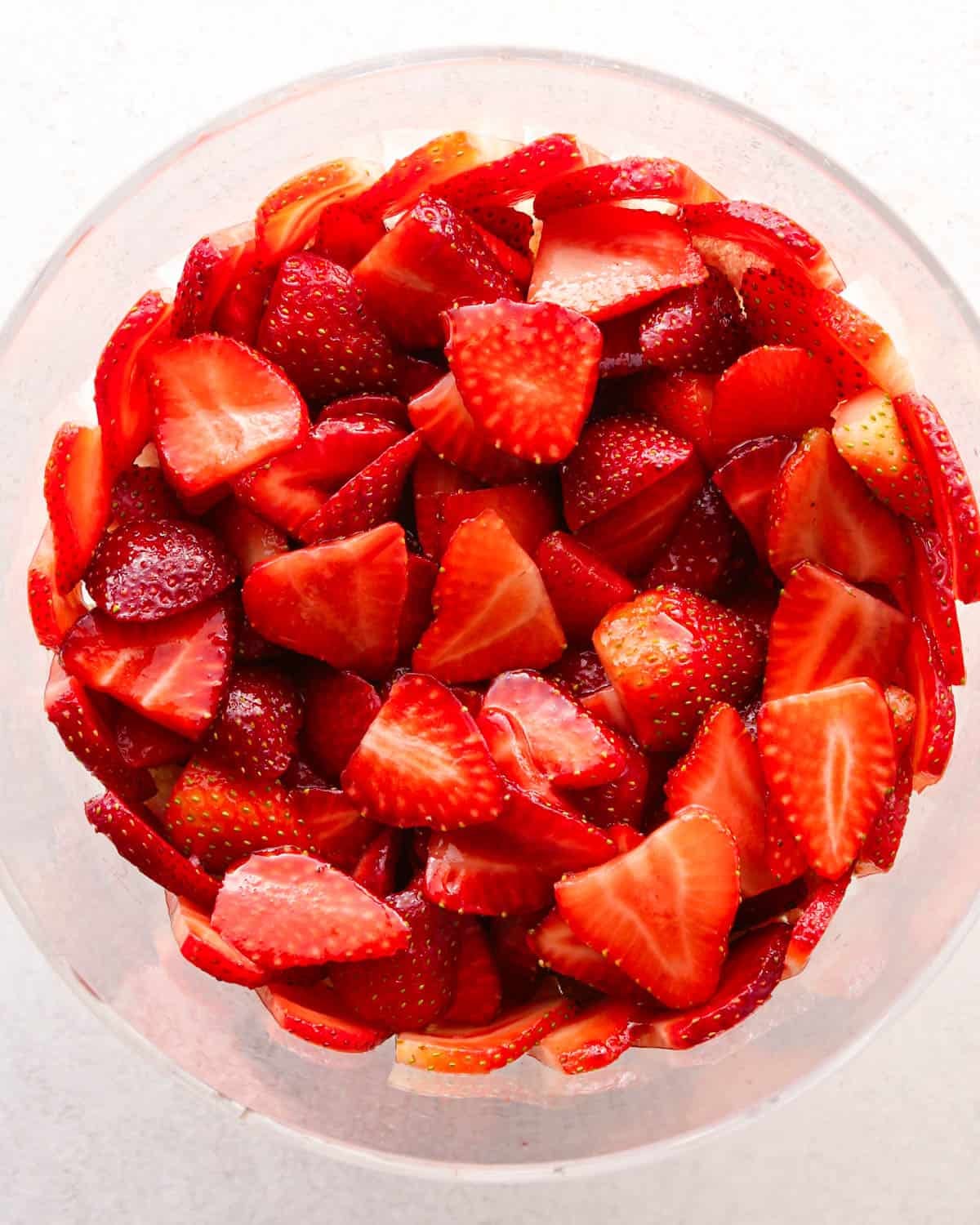 how to make a trifle with berries - sliced strawberries on top of the angel food cake in a glass trifle dish