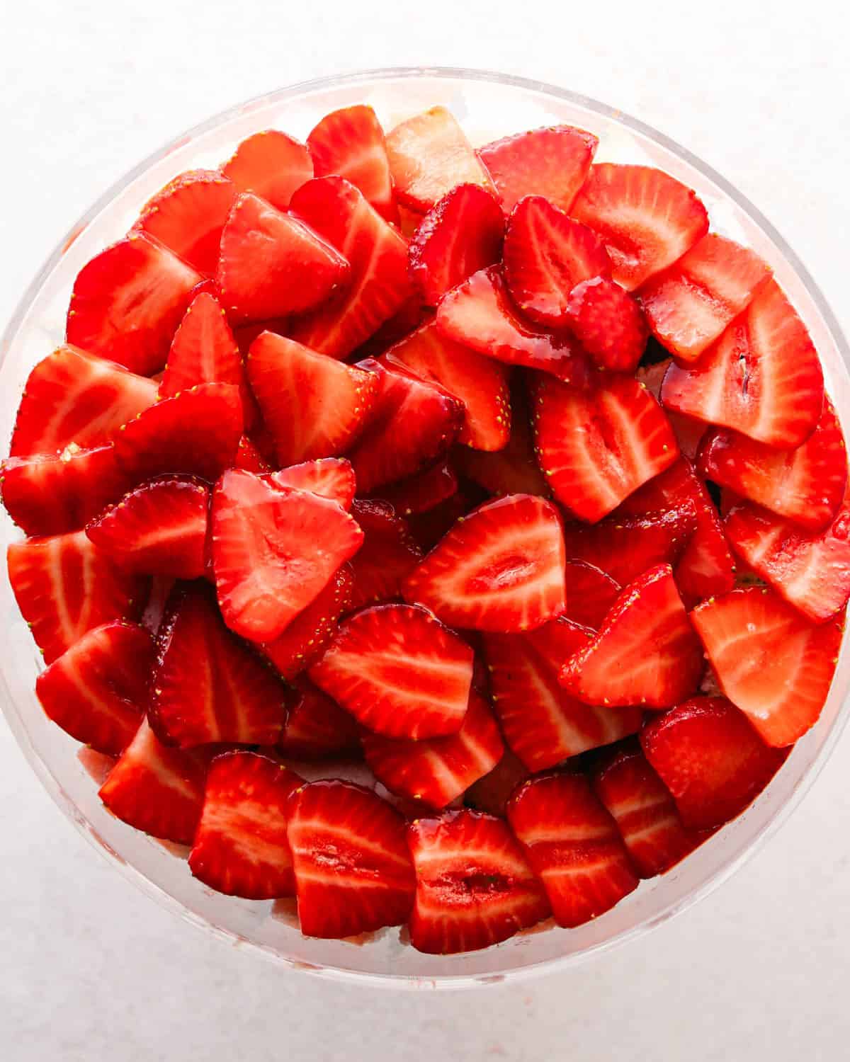 how to make a trifle with berries - sliced strawberries put on top of angel food cake in a glass trifle dish