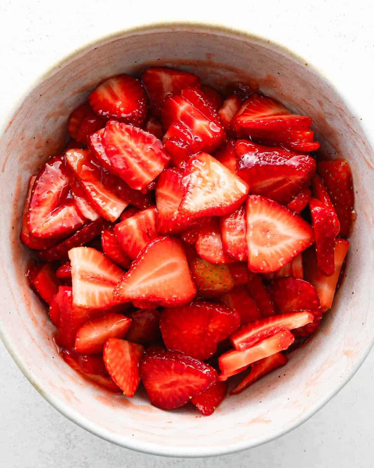 how to make a trifle with berries - strawberries and jam sauce mixed together in a white bowl