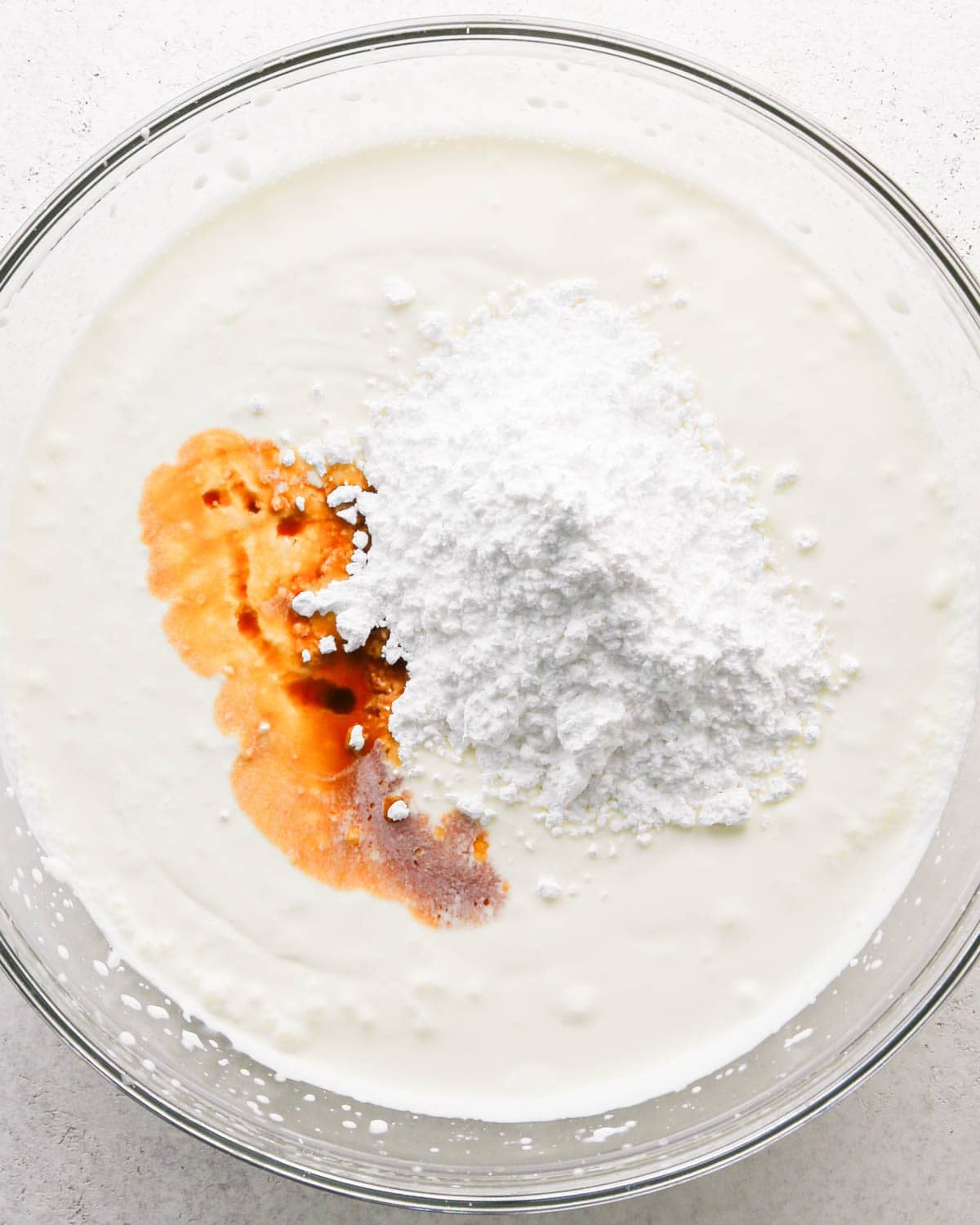 how to make a trifle with berries - making the whipped cream layer in a glass bowl, adding powdered sugar and vanilla