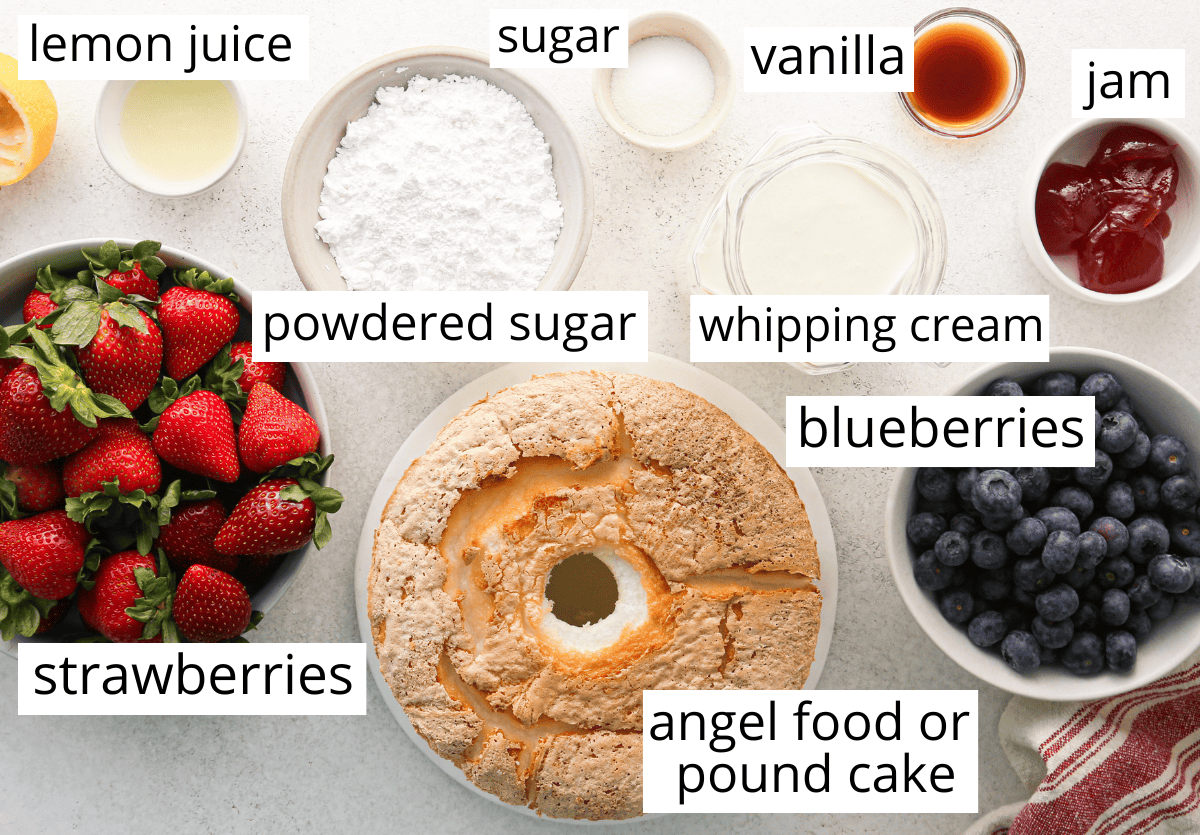 overhead photo of the ingredients in this berry trifle recipe in bowls and labeled including powdered sugar, angel food cake, whipping cream, vanilla, jam, and berries