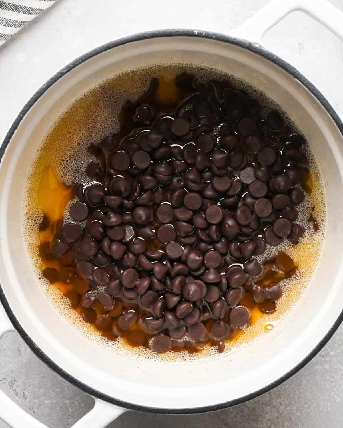 making brown butter brownies - chocolate chips added to the browned butter in a white pot with a black rim