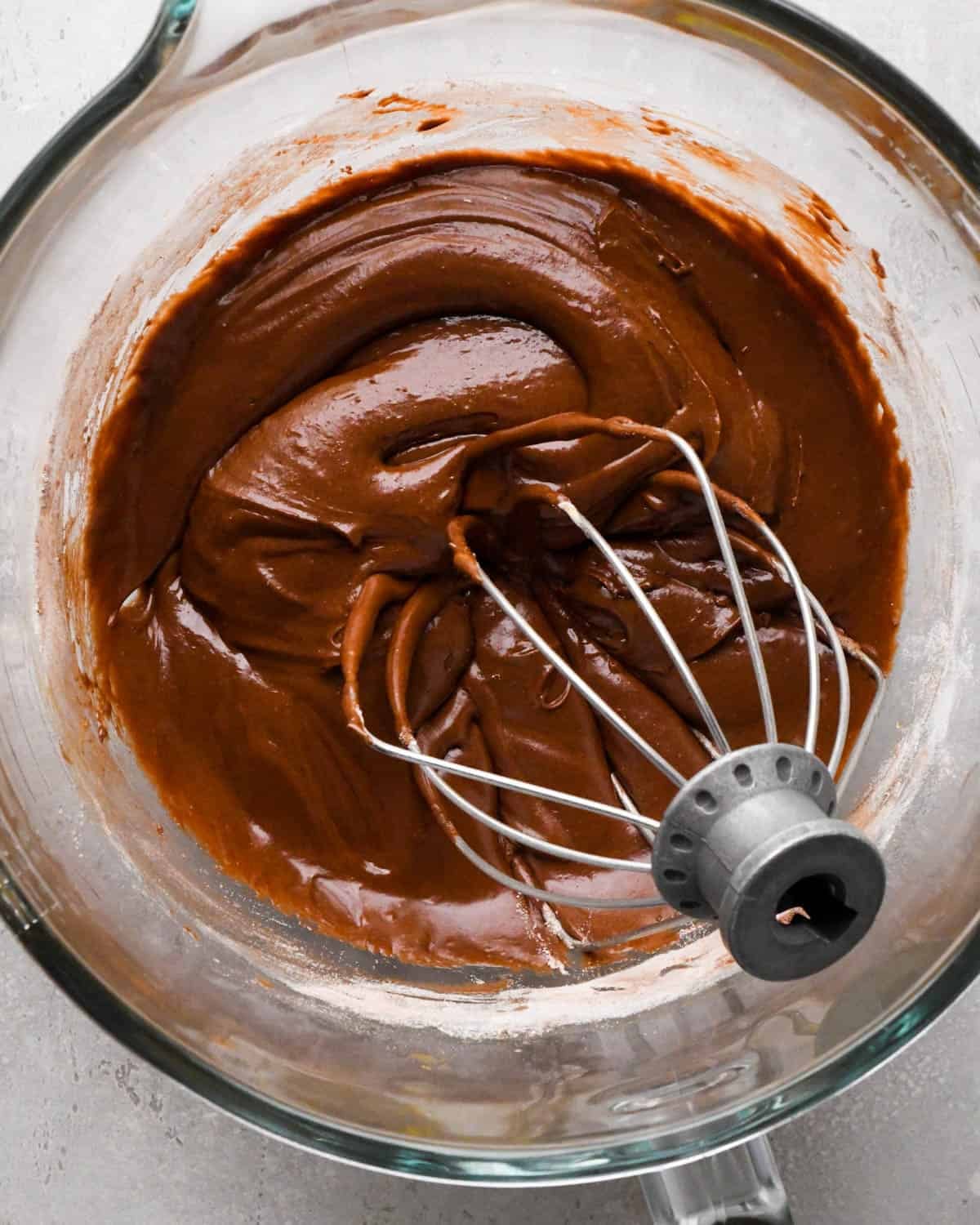 making brown butter brownies - batter in a glass mixing bowl with a wire whisk attachment
