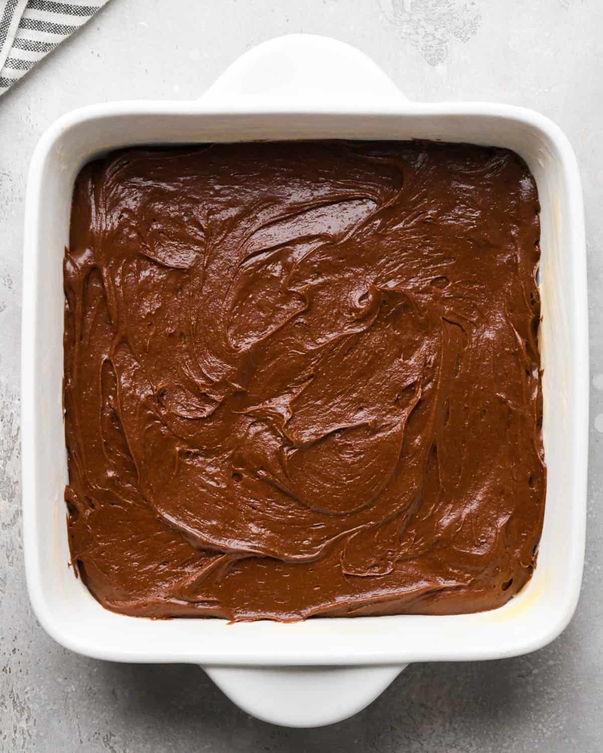 making brown butter brownies - batter spread into a square white baking dish before baking