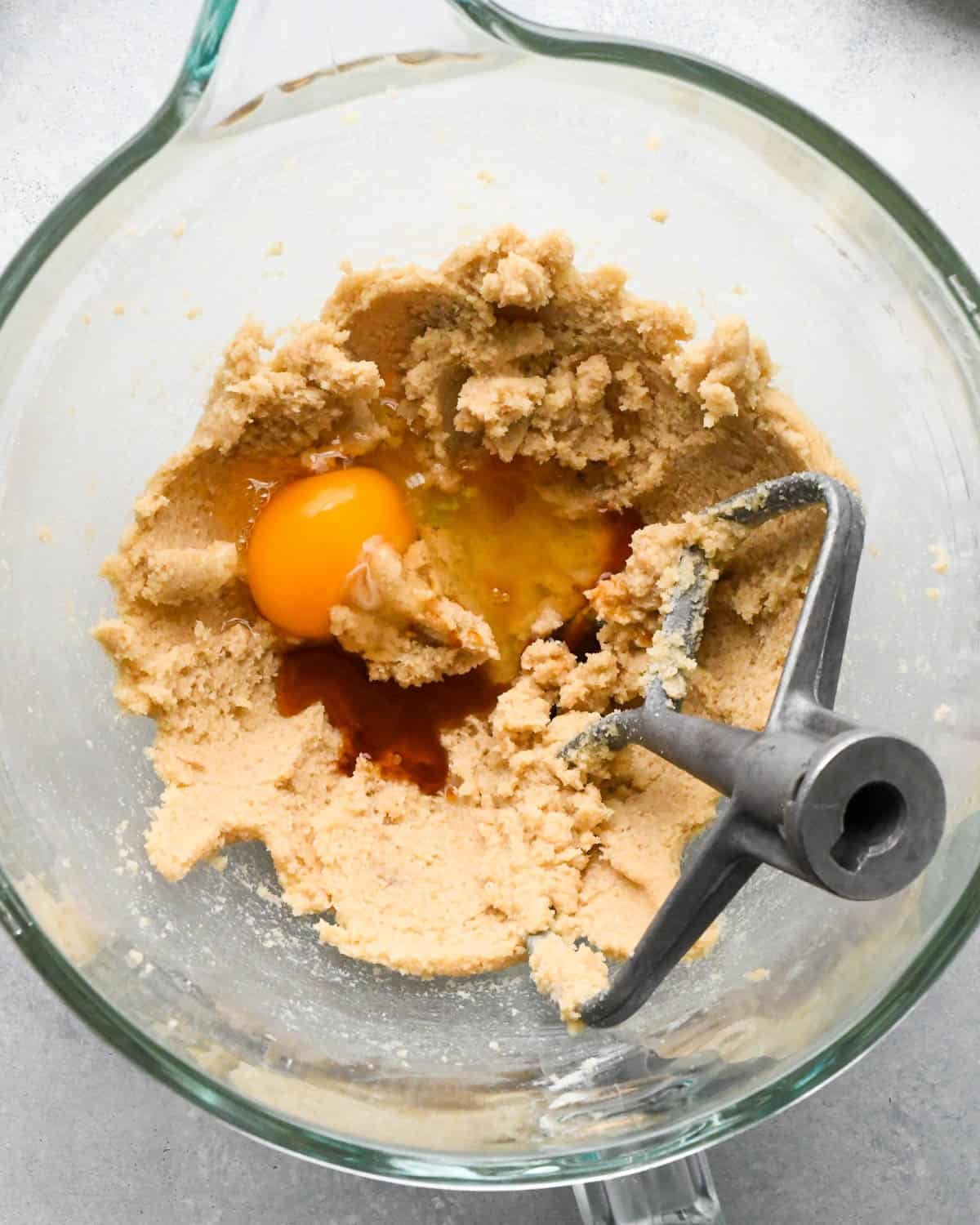 How to Make Chocolate Oatmeal Cookies - egg and vanilla added to the creamed butters and sugars in a glass mixing bowl with a paddle attachment