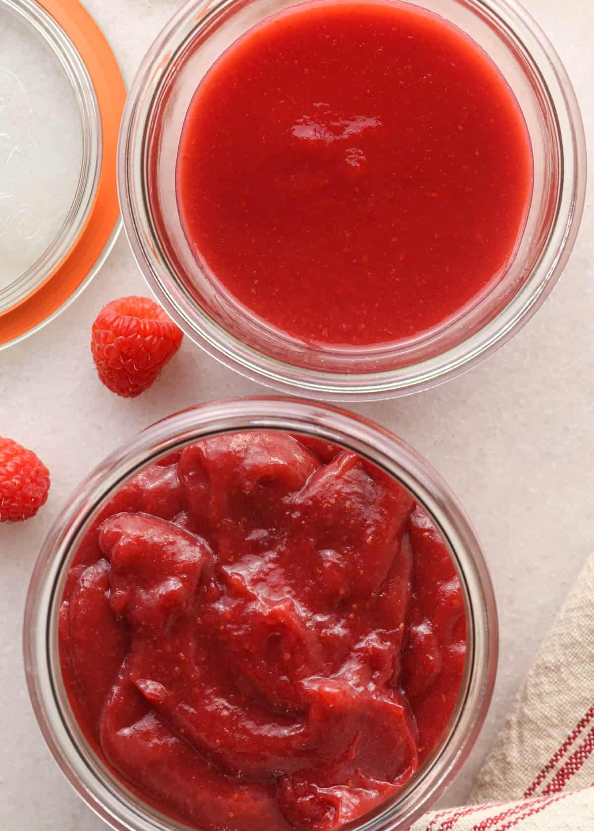 overhead view of two glass jars, one with the raspberry puree for the frosting, and one with the thickened raspberry filling