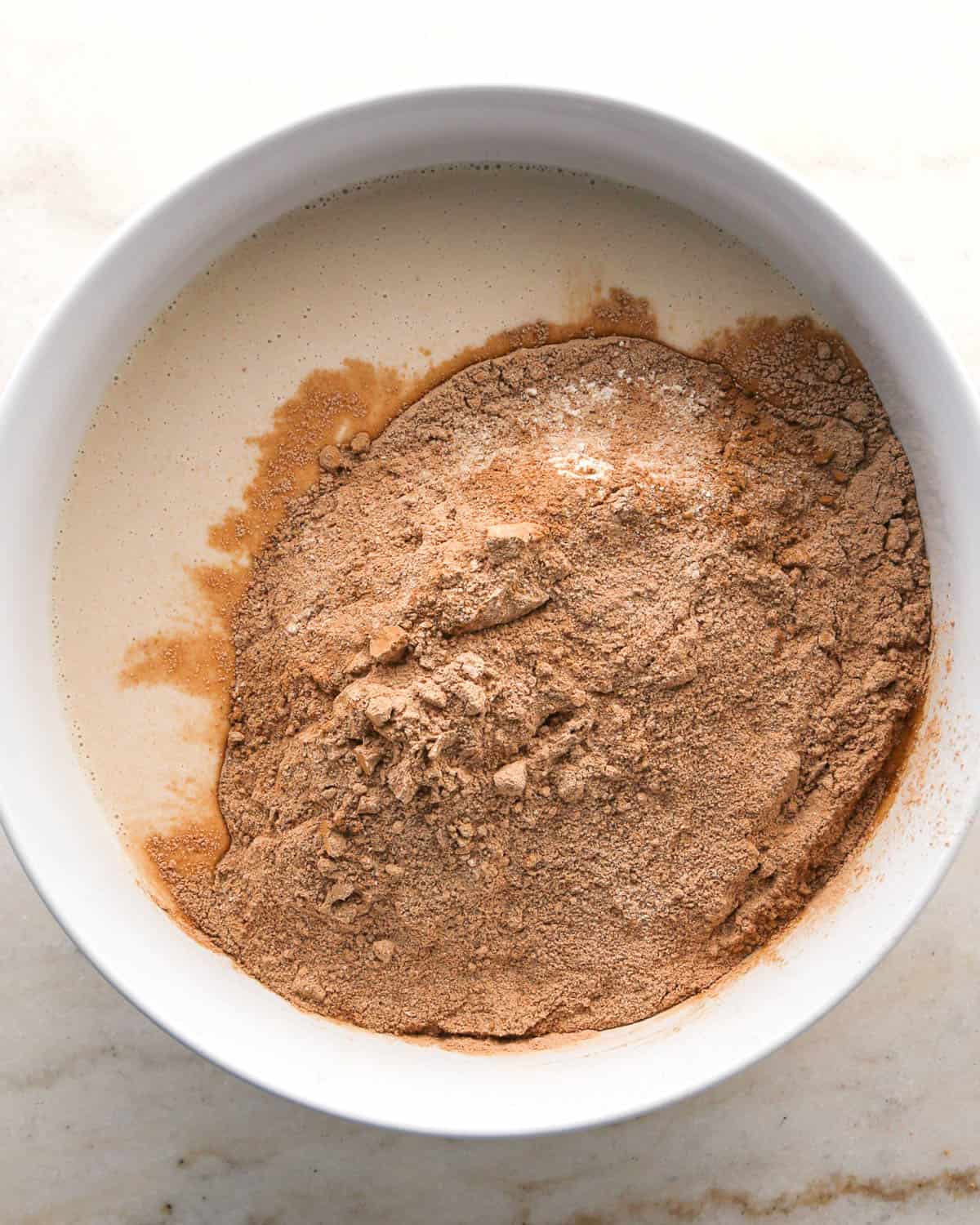 making chocolate raspberry cake - dry ingredient mixture added to the wet ingredient mixture in a glass bowl before mixing