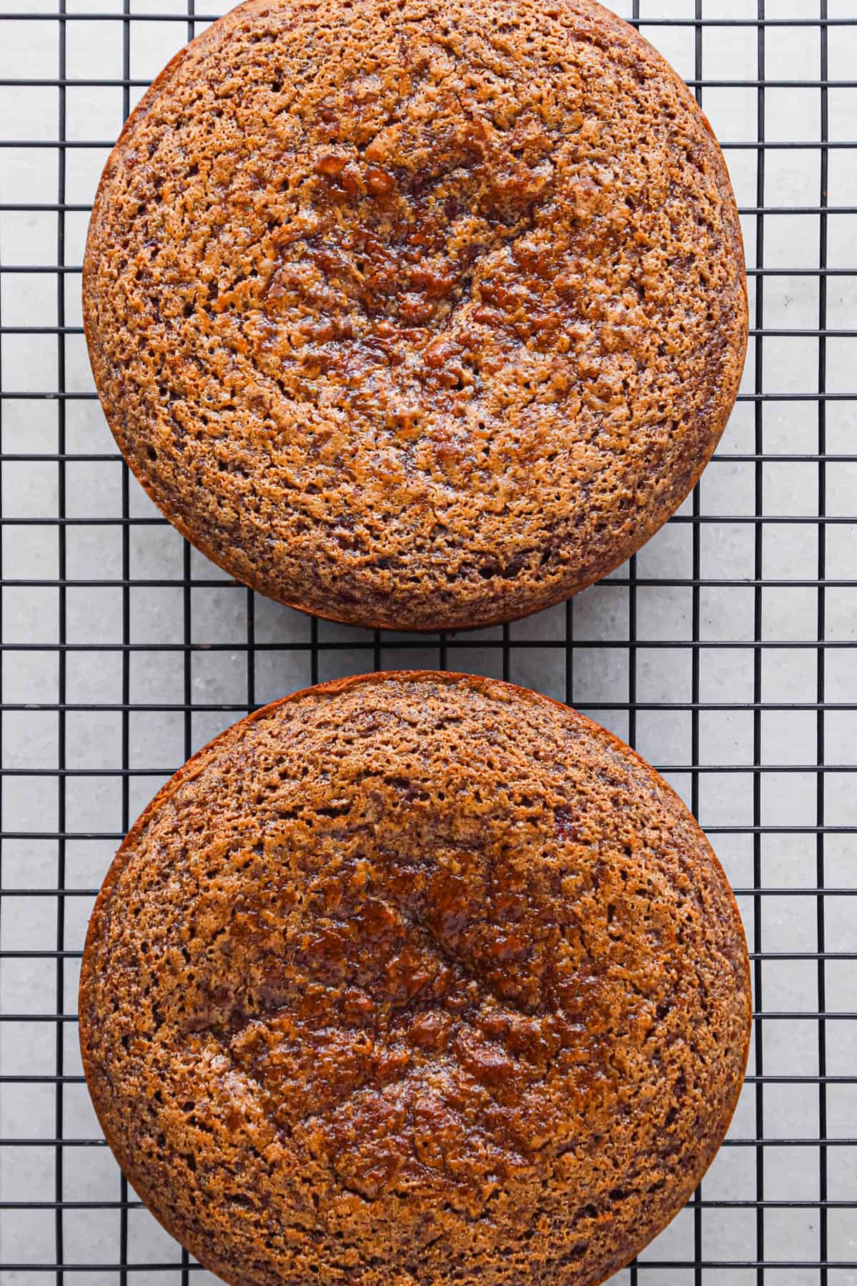 two chocolate raspberry cake rounds out of the cake pans on a wire cooling rack