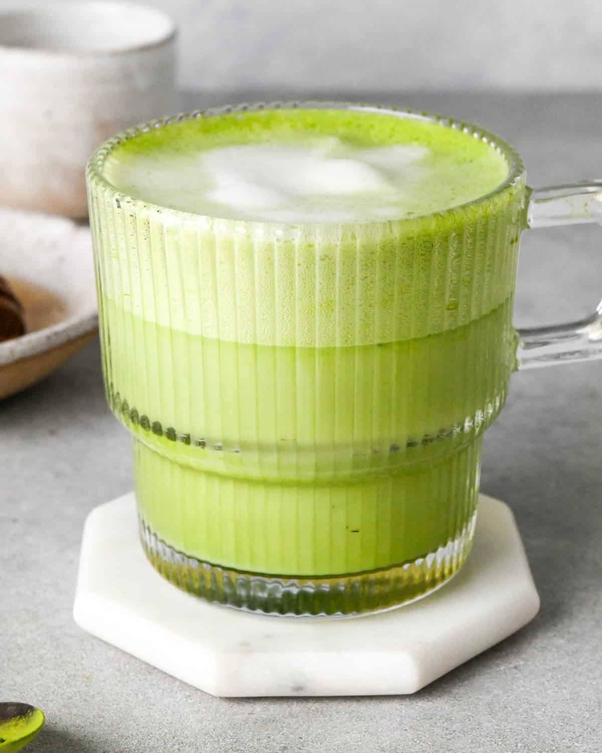 matcha latte in a clear glass mug with a handle with foamy milk on top
