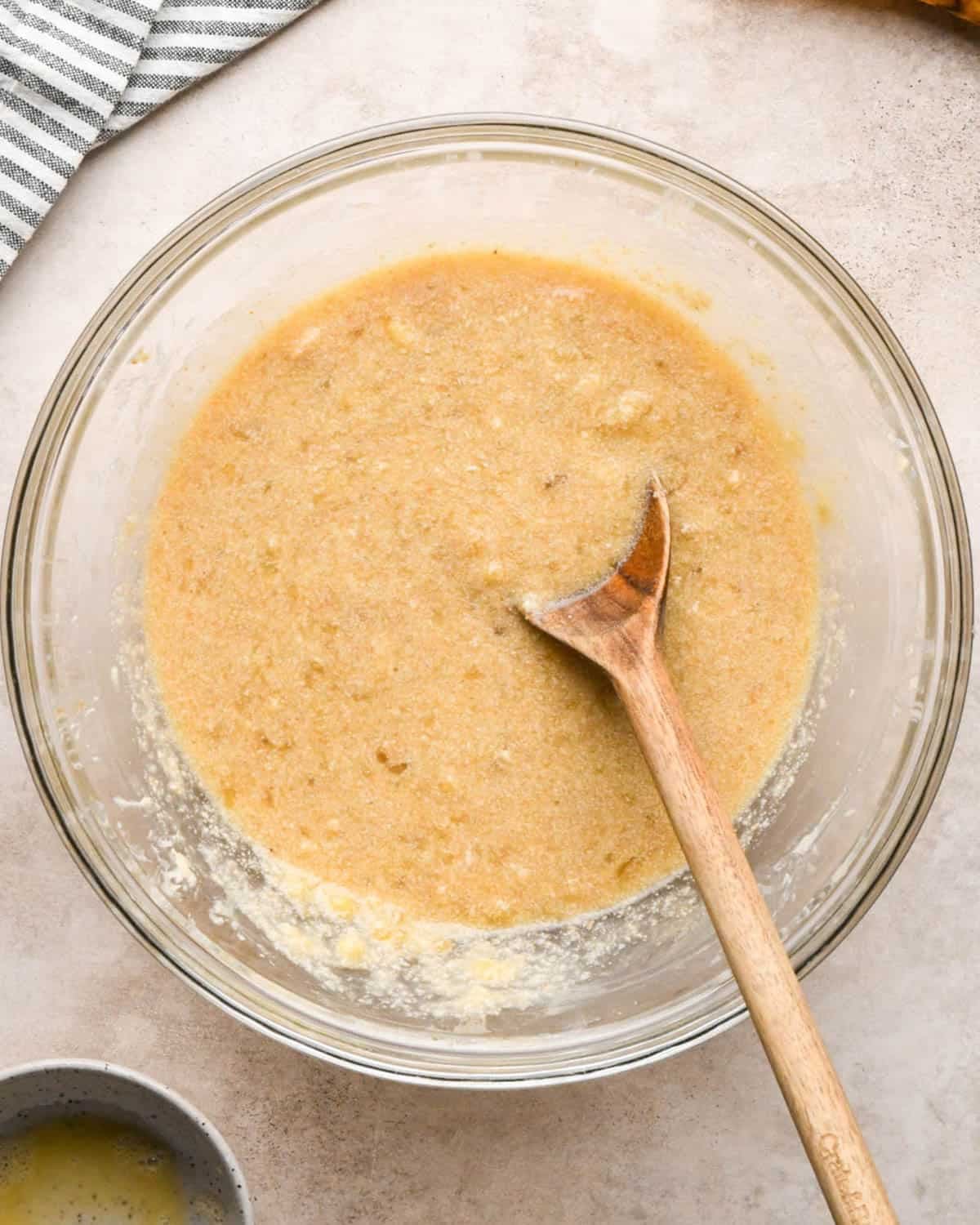 making brown butter banana bread - wet ingredients in a glass bowl with a wooden spoon