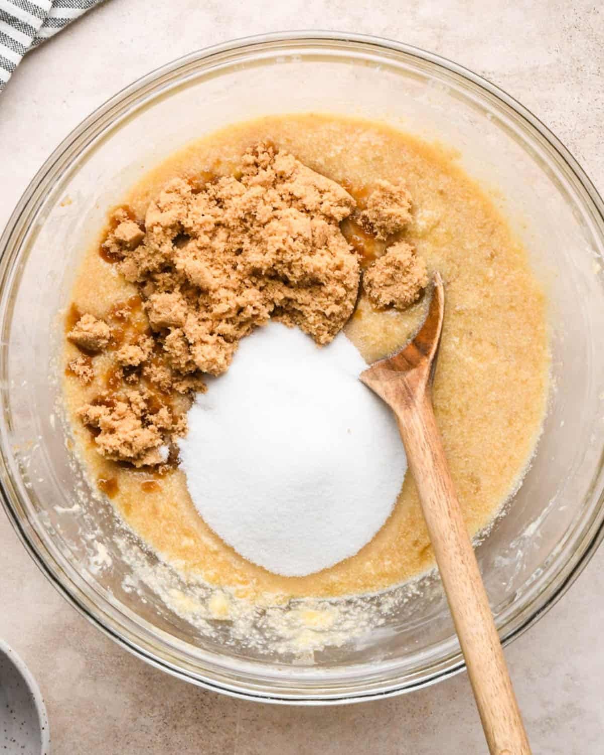 making brown butter banana bread - brown sugar and granulated sugar added to the wet ingredients before mixing in a glass bowl with a wooden spoon