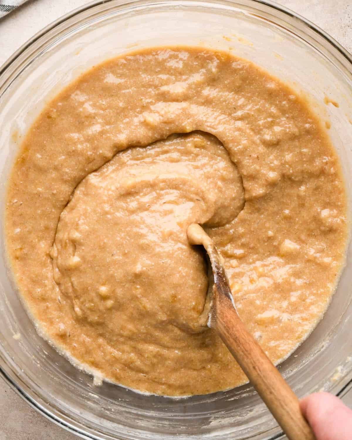 making brown butter banana bread - final batter in a glass bowl with a wooden spoon