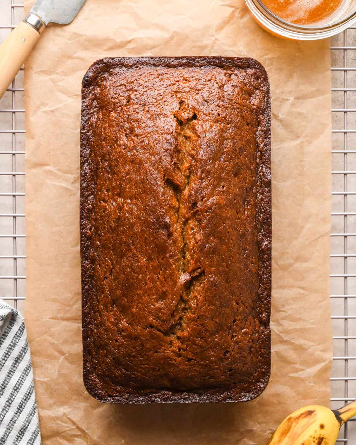 brown butter banana bread on parchment paper on a wire cooling rack