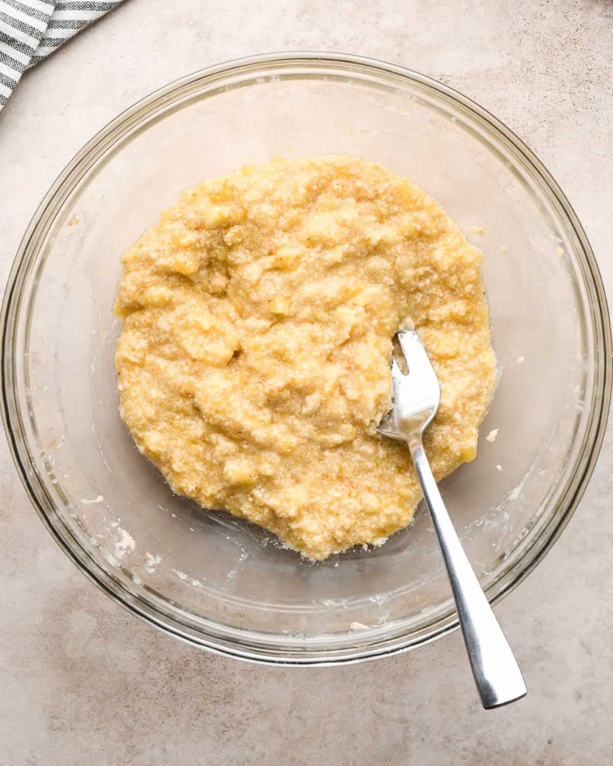 making brown butter banana bread - mashed bananas and brown butter in a glass bowl with a metal fork