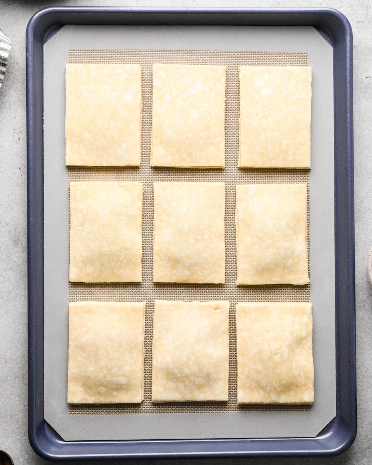 making homemade pop tarts - 9 pop tarts before baking with the top piece of dough put over the filling on a baking sheet lined with a silicone baking mat