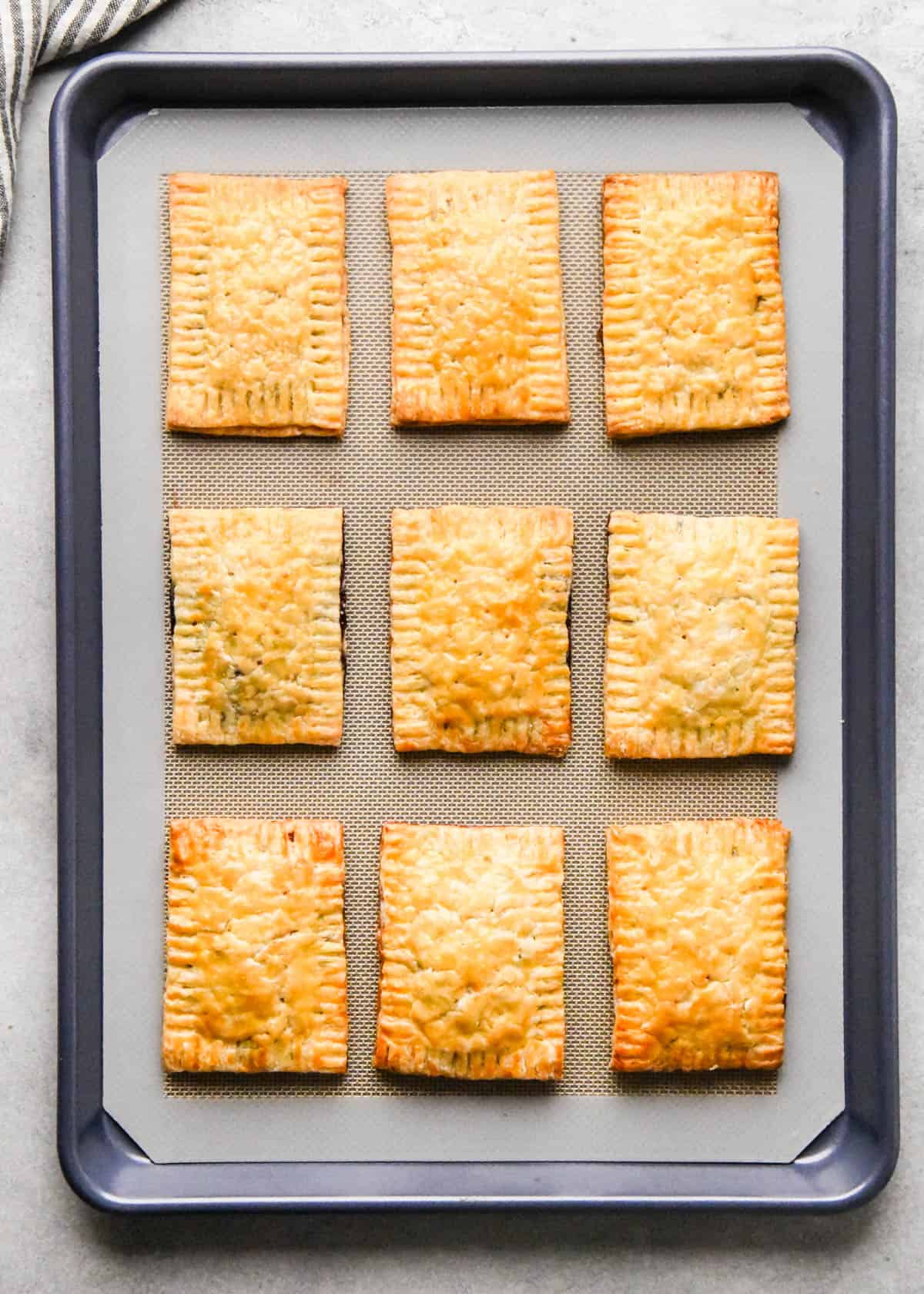 making homemade pop tarts - 9 pop tarts on a baking sheet lined with a silicone baking mat after baking