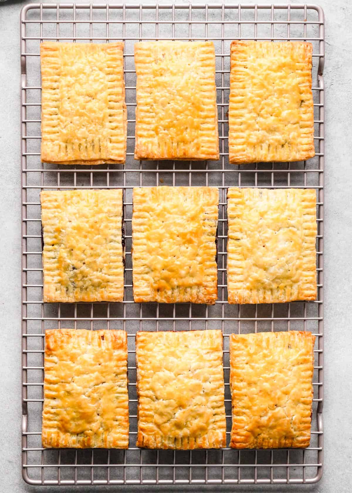 9 homemade pop tarts on a wire cooling rack after baking