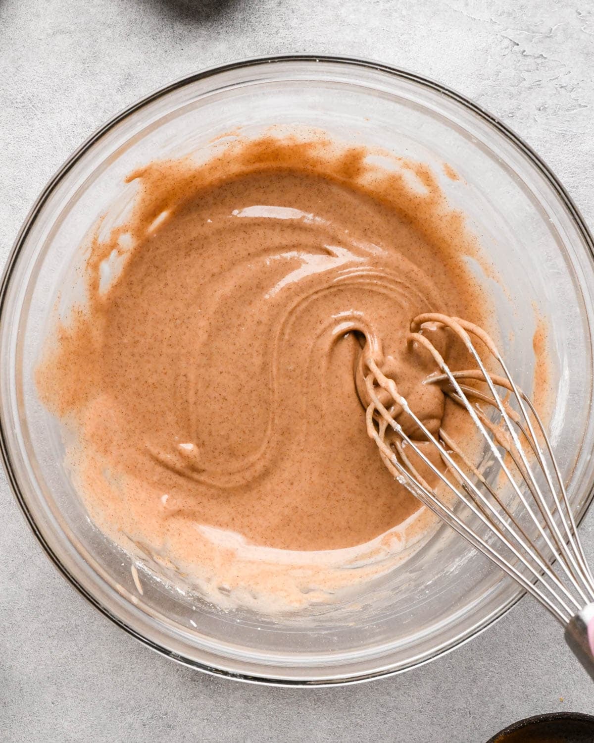 making icing for homemade pop tarts - cinnamon icing in a glass bowl being whisked with a metal whisk
