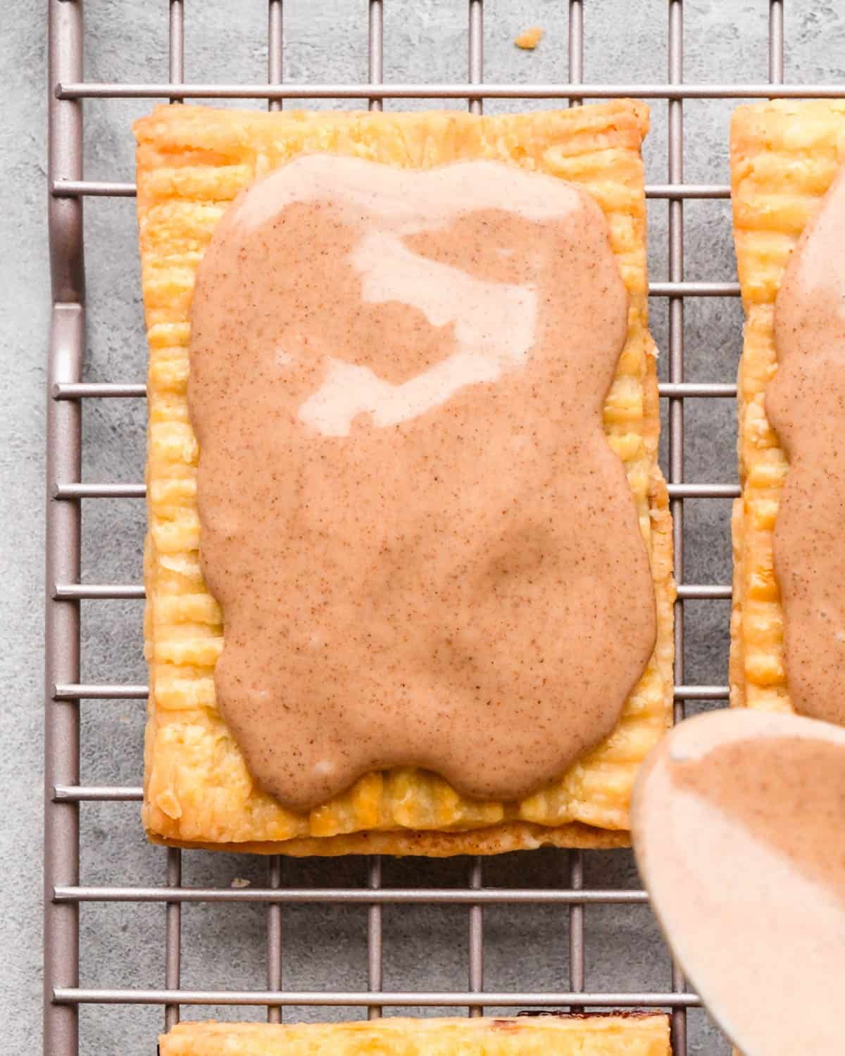 a cinnamon sugar pop tart on a wire cooling rack after the glaze has been spread on top