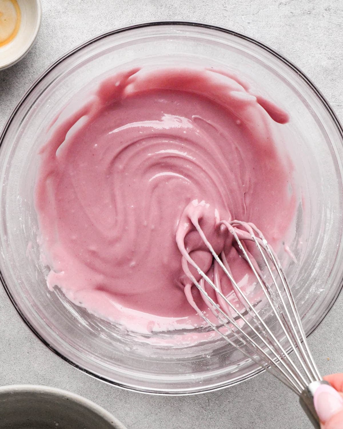 making icing for homemade pop tarts - blackberry icing being whisked together in glass bowl with a wire whisk