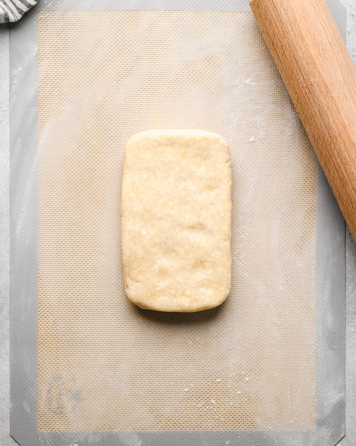 making homemade pop tarts - one rectangle of dough on a mat with a rolling pin