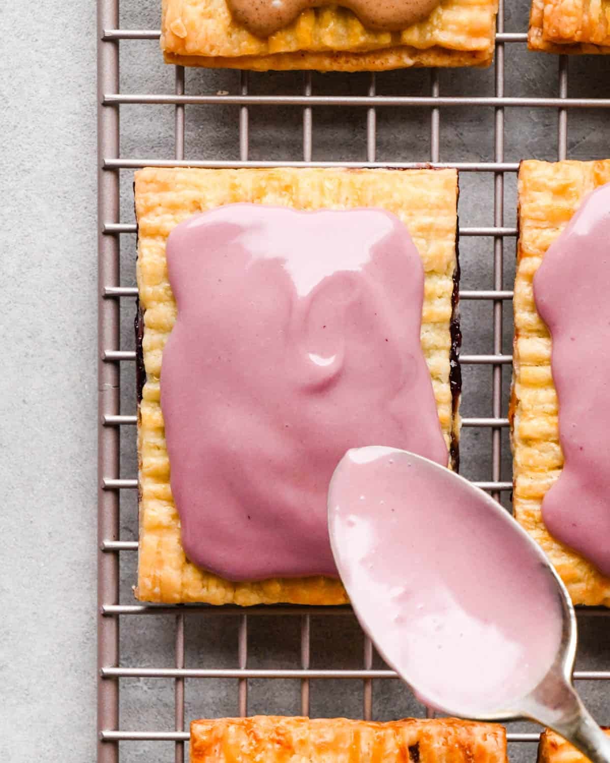 a blackberry pop tart on a wire cooling rack after the glaze has been spread on top