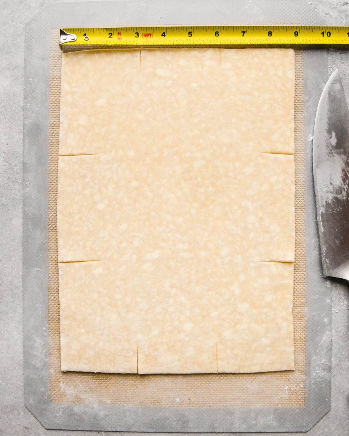 making homemade pop tarts - a rectangle of dough being scored before cutting using a tape measure to measure the size