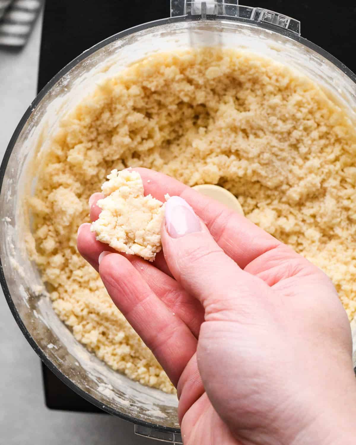 making homemade pop tarts - a hand pinching the dough mixture together over the food processor container