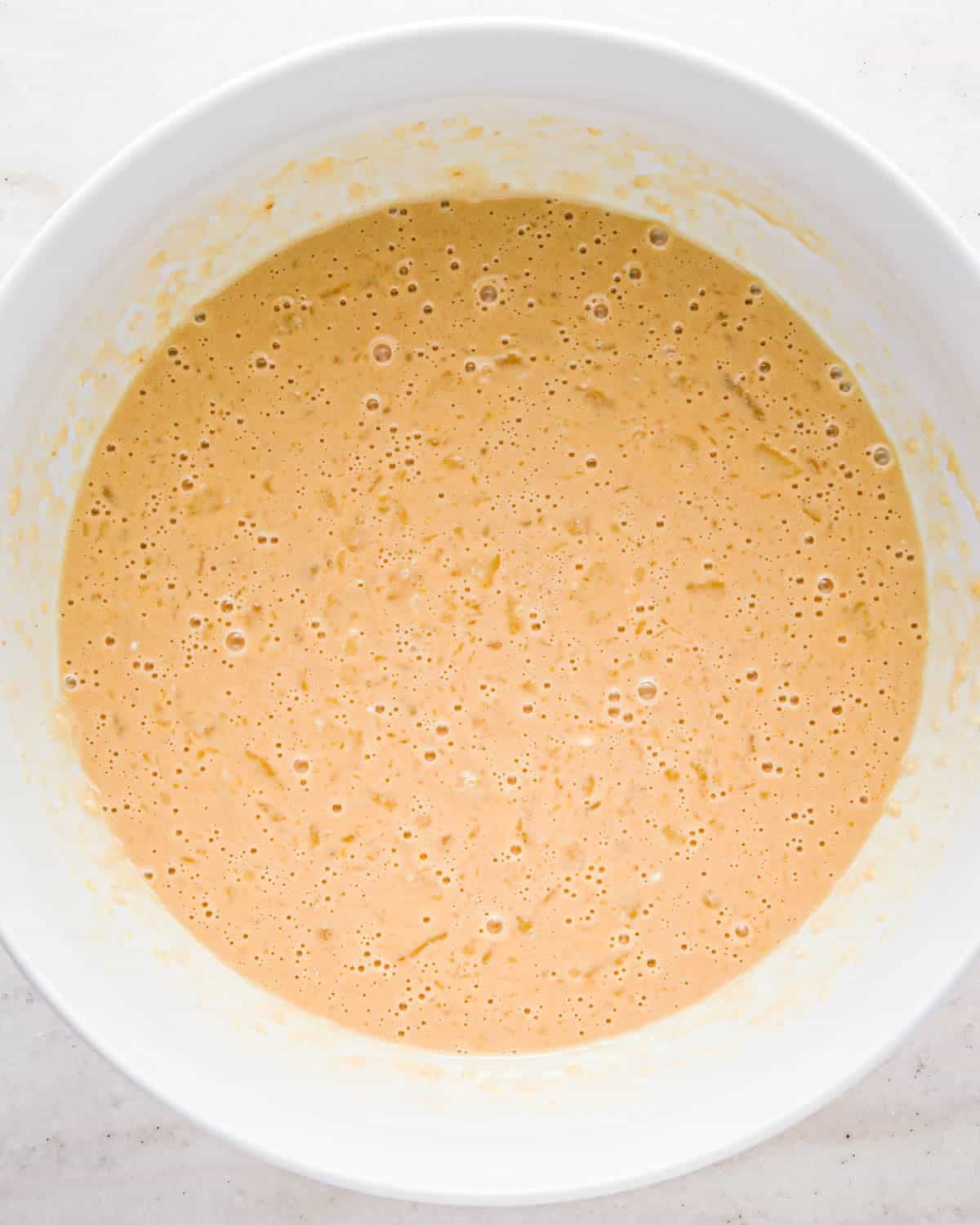 making oatmeal chocolate chip muffins - wet ingredient mixture in a white bowl after mixing
