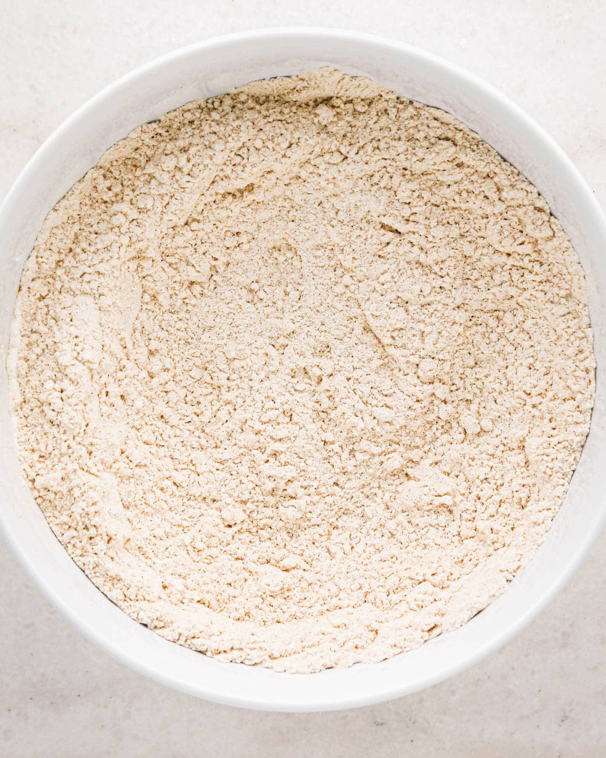 making oatmeal chocolate chip muffins - flour, baking soda, baking powder, cinnamon and salt in a white bowl after mixing