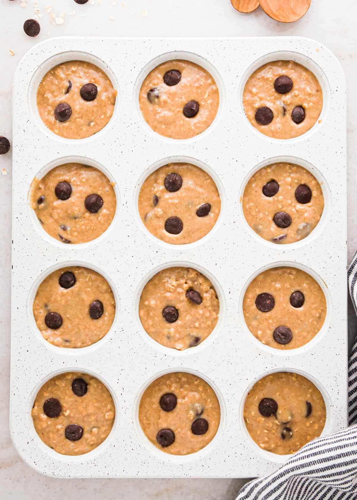 making oatmeal chocolate chip muffins - 12 wells of a white muffin pan filled with batter