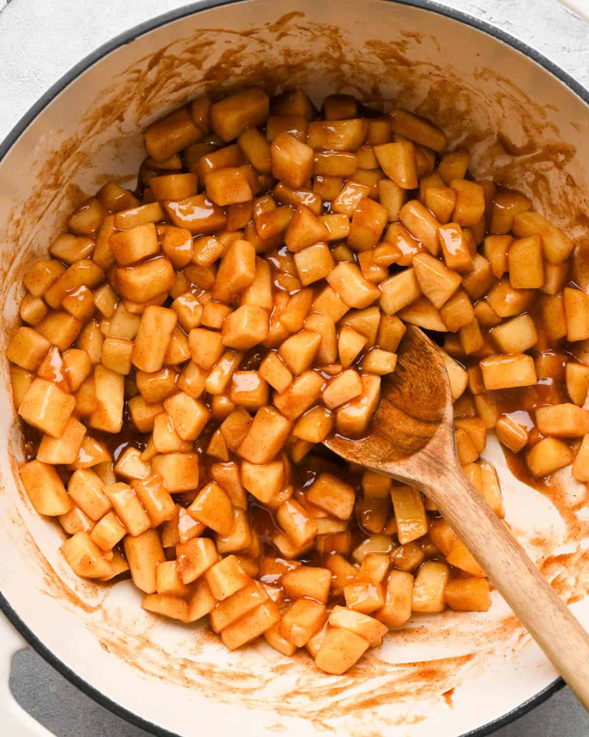 final apple hand pies filling in a white pot with a wooden spoon.