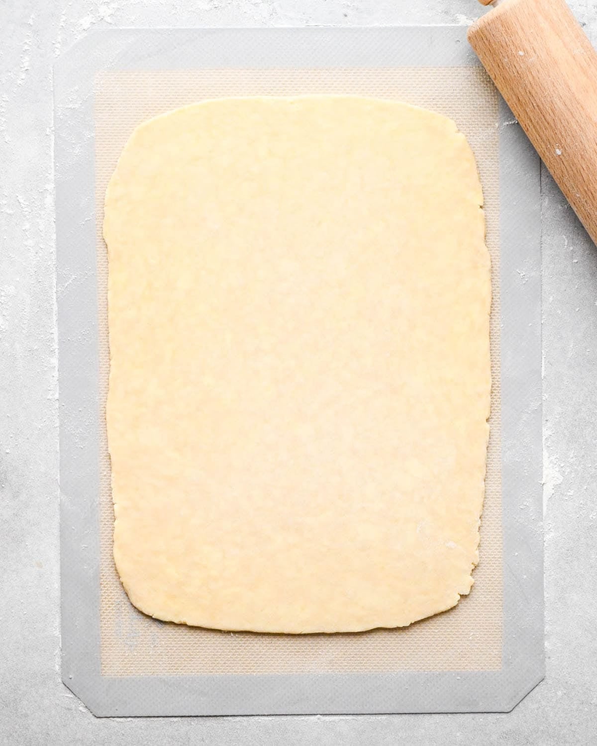 making apple hand pies crust - dough rolled into a large rectangle on a floured silicone baking mat