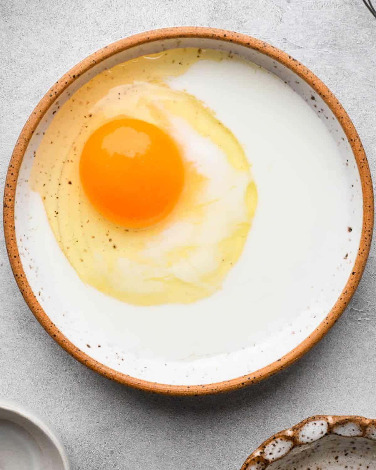egg and cream in a small ceramic bowl before mixing