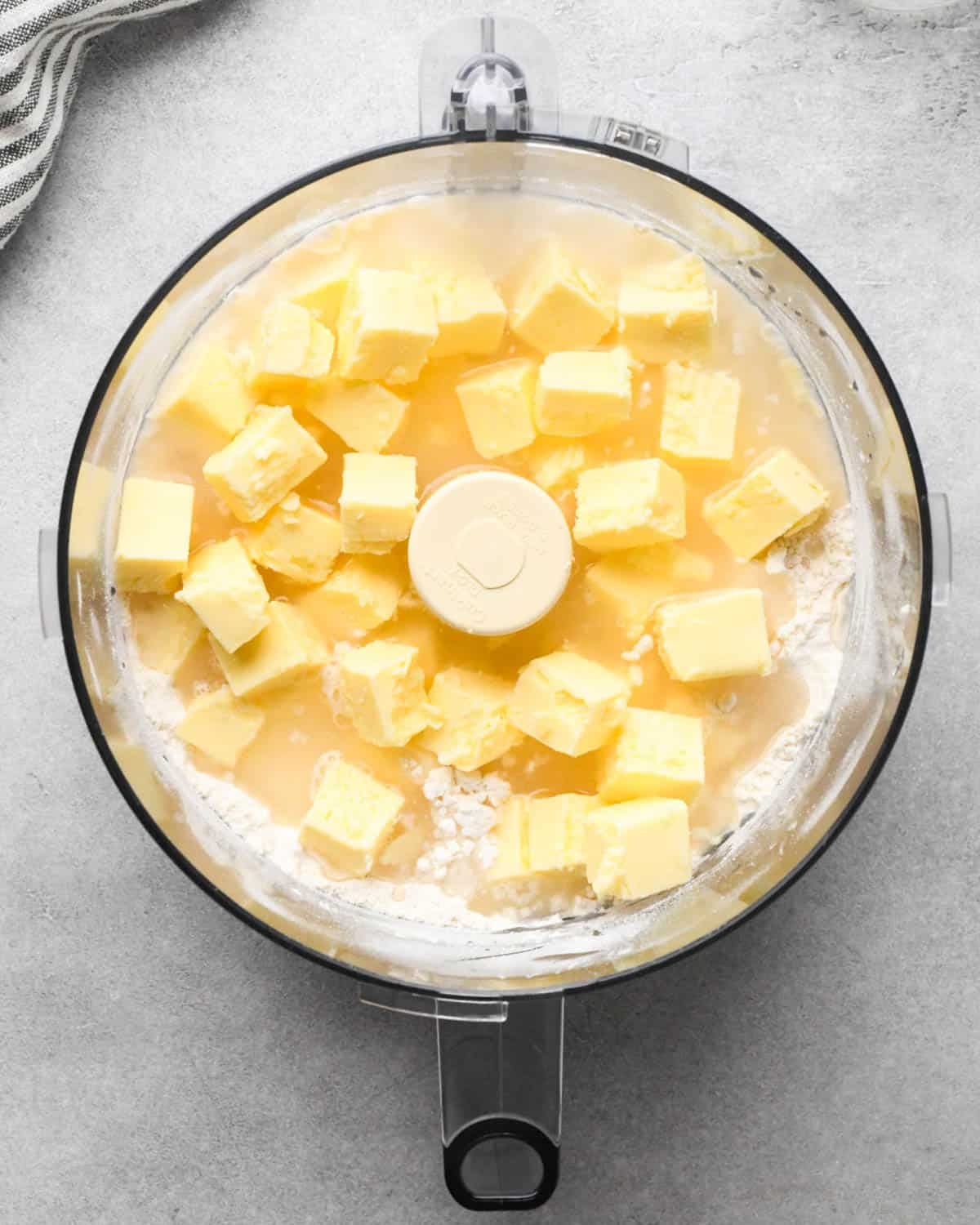 making apple hand pies crust - cubed butter and water added to the flour in the food processor before mixing