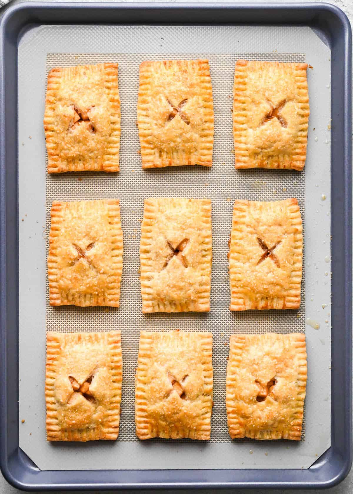9 baked apple hand pies on a baking sheet