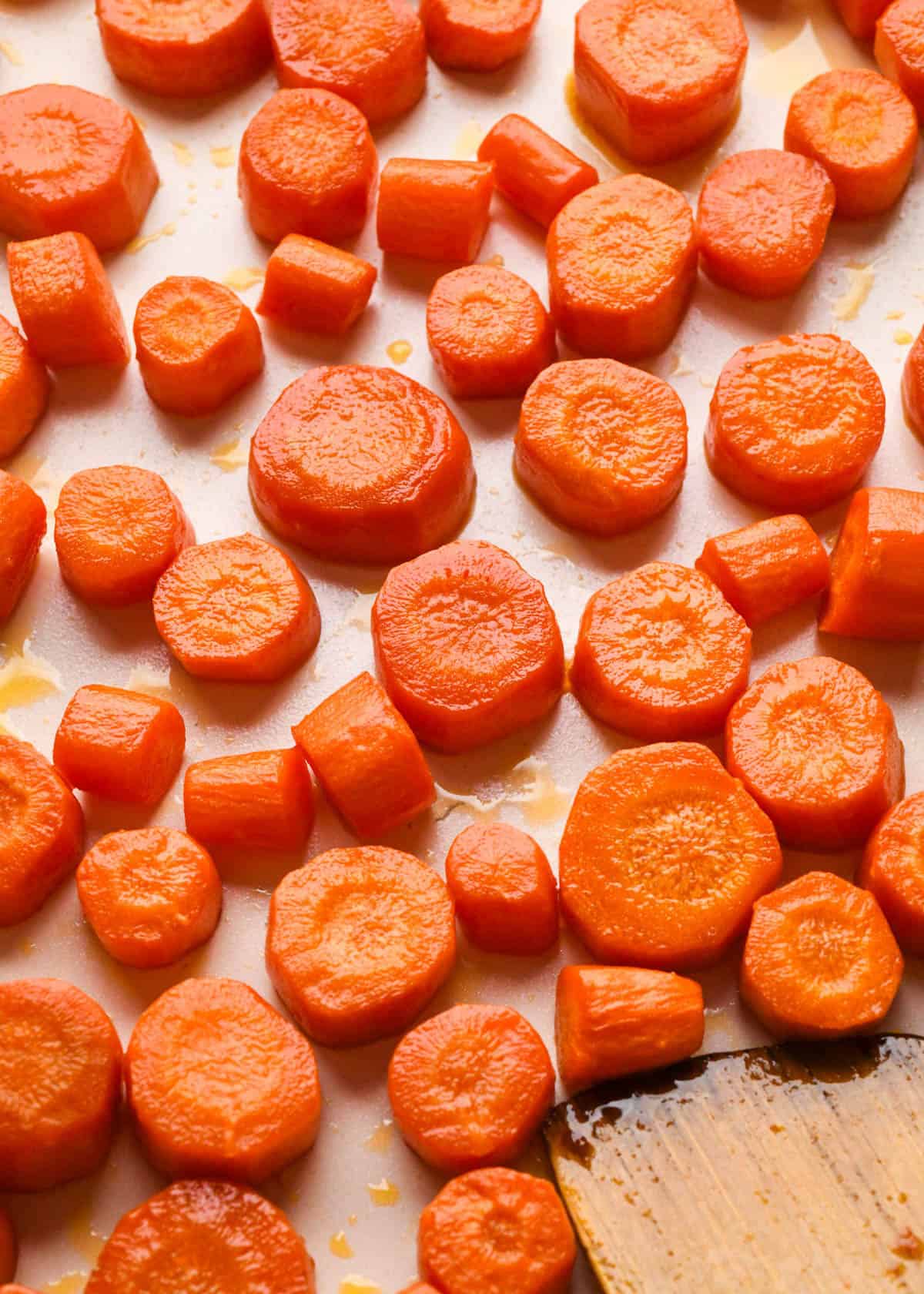 perfectly golden maple glazed carrots on a white baking sheet