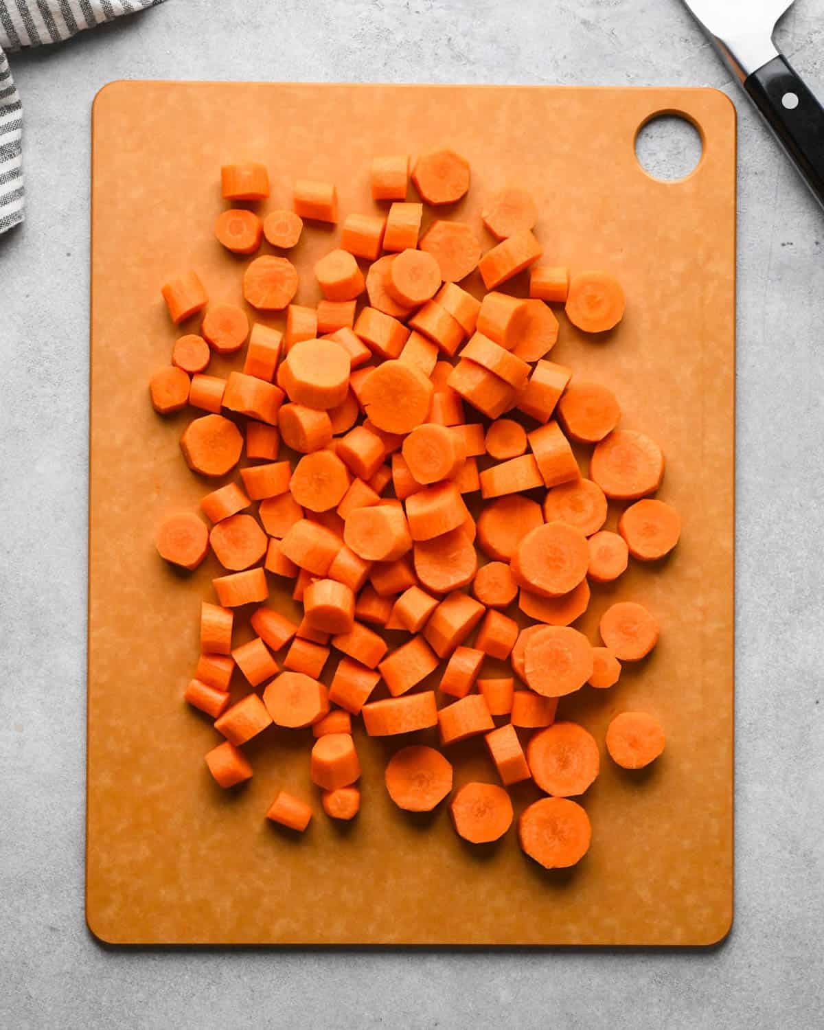 making glazed maple carrots - peeled carrots cut into circles on a brown cutting board