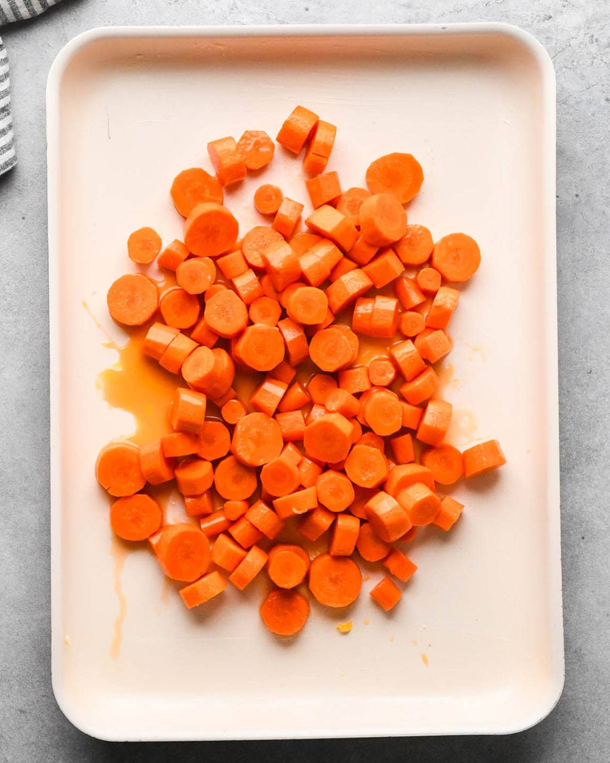 making glazed maple carrots - carrot and glaze mixture put on a baking sheet before spreading out